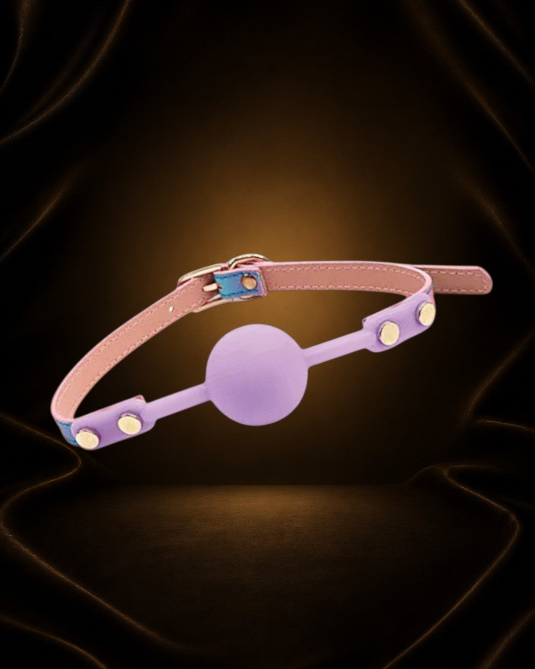 Mordaza ajustable Éxtasis Boutique de silicona rosa con detalles dorados y correa de cuero vegano iridiscente.